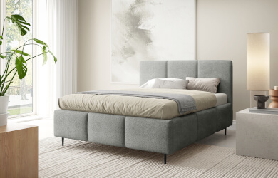 szare łóżko tapicerowane na metalowych czarnych nóżkach, posiada dekoracyjne przeszycia